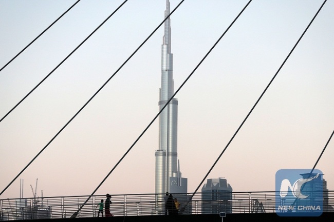 A picture taken on April 4, 2017, shows the Burj Khalifa, the world's tallest tower, dominating pedestrians crossing a bridge over the water canal, which links the city's business hub to the Gulf. [Photo: Xinhua/AFP Photo]