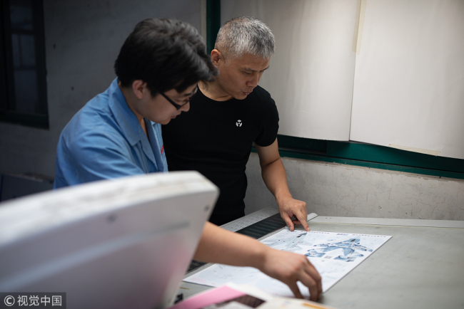 Liu Dong (right) checks a drawing. [Photo/VCG]