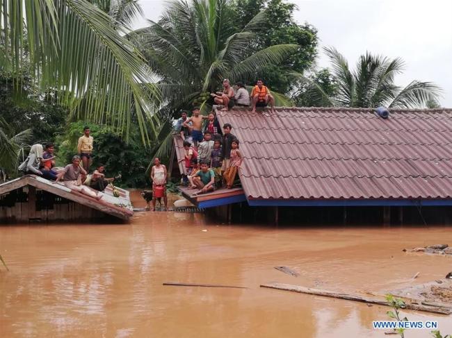 Villagers are seen stranded on rooftops of houses after an under-construction dam collapsed in Attapeu, Laos, on July 24, 2018. [Photo: Xinhua/Vilaphon Phommasane]