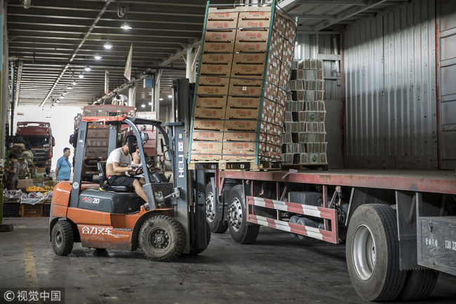 A man uses a forklift to unload a pallet of imported fruit from a truck at a wholesale market in Shanghai, China, on Friday, July 13, 2018. [Photo: VCG]