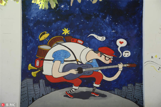 A man playing a guitar is painted on a wall along a street in Guiyang city, Southwest China's Guizhou province, July 29, 2018. [Photo/IC]