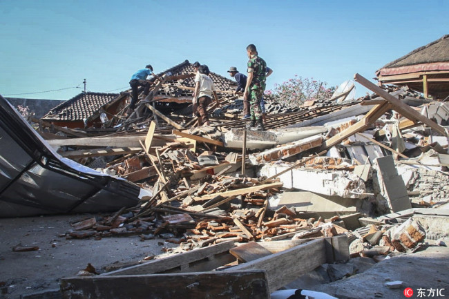 Indonesian rescuers search for victims under the ruin of a collapsed house after an earthquake struck in North Lombok, West Nusa Tenggara, Indonesia, 06 August 2018. According to media reports, a 7.0 magnitude quake hit Indonesia's island of Lombok on 05 August, killing at least 91 people. [Photo; IC]