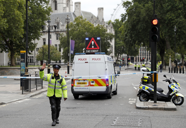 A police officer gestures as he stands in a road in central London, after a car crashed into security barriers outside the Houses of Parliament, in London, Tuesday, Aug. 14, 2018. [Photo: AP/Alastair Grant]