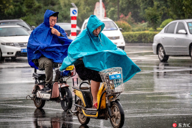 People wearing raincoat travel in the rain in Huaxian County, Henan Province. [Photo: IC]