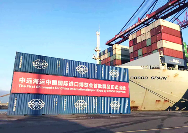 A banner hangs on the covers of containers, stating "The First Shipments for China International Import Expo by COSCO SHIPPING" [Photo provided by COSCO to thepaper.cn]
