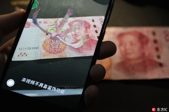 An animation of a phoenix appears above a 100 yuan at the launch of a new QQ app feature that aims to teach users how to spot counterfeit notes, seen here on Tuesday, September 11, 2018. [Photo: IC]