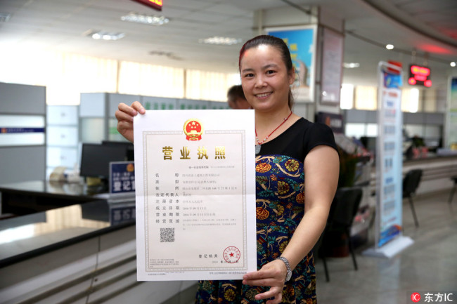 A woman in Sichuan Province holds a business license of her company, September 13, 2016. [Photo: IC]