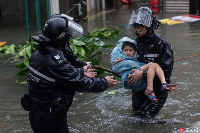 Police officers rescue a child from a flooded street during Typhoon Mangkhut in Lei Yu Mun, Hong Kong, China, September 16 2018.[Photo:IC]