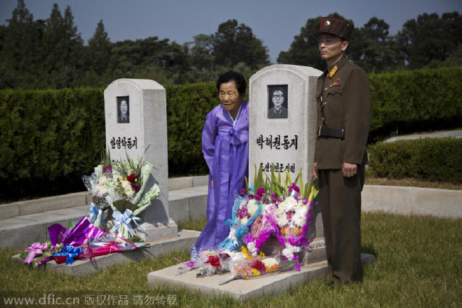 The picture taken on Sept 19, 2013, shows people from DPRK standing together for a portrait next to family member's grave at a cemetery as they observe Chuseok, in Pyongyang. [Photo/IC]