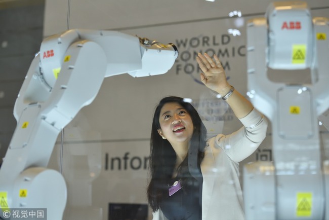 A woman experiences a perceptual robot at the 2018 Summer Davos Forum in Tianjin on September 17, 2018. [Photo: VCG]