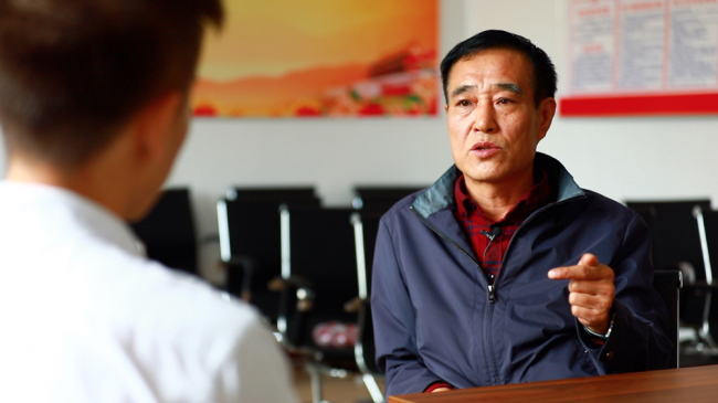 Zhang Shuchun (R), director for the Department of Agricultural Technology Extension in Suihua's Beilin District, speaks with CGTN in his office. [Photo: CGTN]