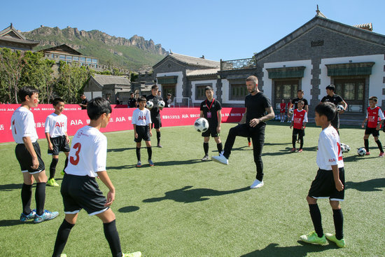 British football star David Beckham plays the football with children on Sept. 23. [Photo: people.com.cn]