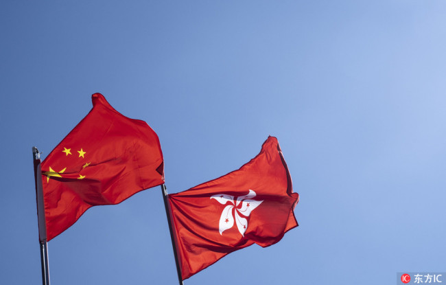 This picture taken on July 28, 2018 shows a Hong Kong flag (L) and a Chinese national flag fluttering in the wind. [Photo: IC]