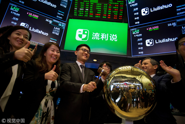 Yi Wang, founder and chief executive officer of Laix Inc., center, rings a ceremonial bell during the company's initial public offering (IPO) on the floor of the New York Stock Exchange (NYSE) in New York, U.S., on Thursday, Sept. 27, 2018. [Photo: VCG]