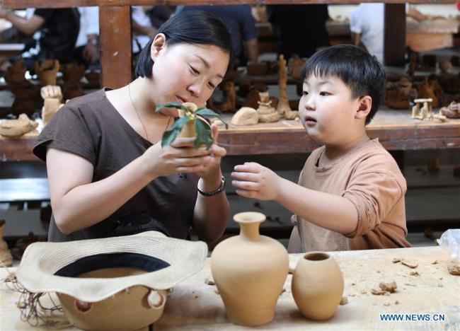 Tourists get hands-on experience(体验) at a pottery workshop(工作室) in Gangyao Village of Yiwu, east China's Zhejiang Province, Oct. 4, 2018. (Xinhua/Gong Xianming)
