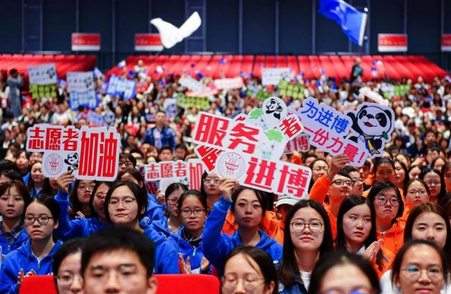More than 5,000 volunteers for the upcoming CIIE pledged responsibility and commitment during the ceremony on Saturday. The ceremony also unveiled CIIE volunteers' outfits and a theme song. [Photo: Xinhua]