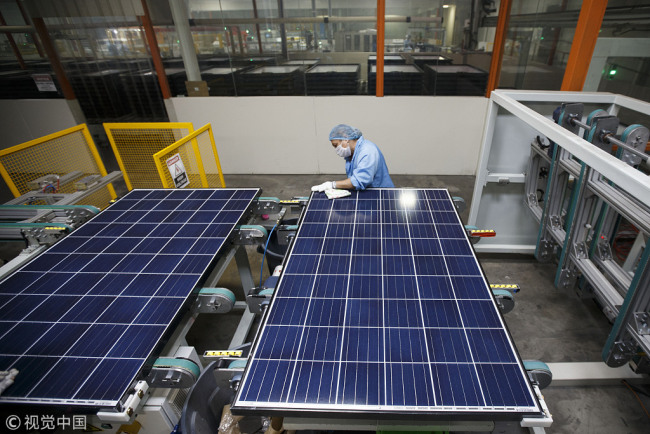 A worker cleans the surface of solar panels during production at the SunSpark Technology Inc. manufacturing facility in Riverside, California, U.S., on Tuesday, April 3, 2018. [Photo: VCG]