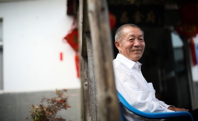 Yan Jinchang sits in the yard at his restaurant. He was one of the 18 farmers who signed the secret agreement in 1978. [Photo: China Plus/ Li Jin]