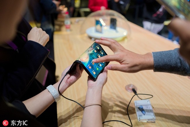 Customers try out the large-screen foldable devices launched by Royole Corp, a manufacturer of flexible displays and smart devices, during a press conference in Beijng, China, October 31.[Photo: IC]