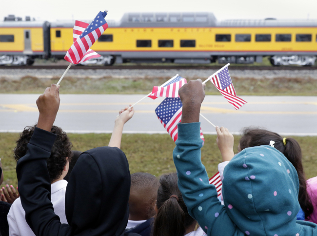 Students from Salyer Elementary School wave flags as the train carrying the body of former president George H.W. Bush travels past their school on the way to Bush's final internment Thursday, Dec. 6, 2018, in Spring, Texas. [Photo: AP/Michael Wyke]