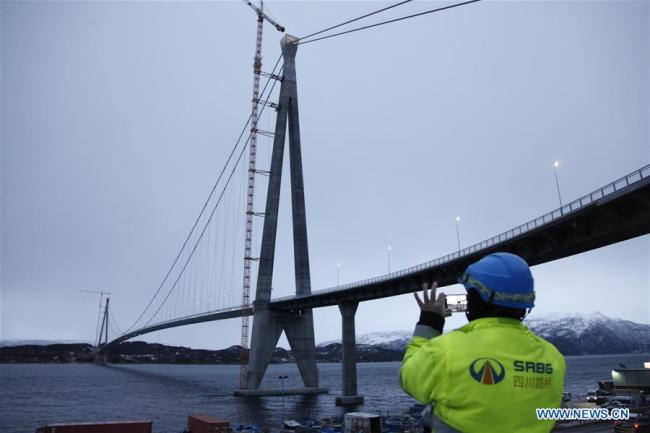 A Chinese worker takes photos of the Halogaland Bridge near Norway's northern port city of Narvik, Dec. 9, 2018. A ceremony was held Sunday to officially open Norway's second largest bridge that has been built by a Chinese company and its partners some 220 km inside the Arctic Circle. With a total length of 1,533 meters and a free span of 1,145 meters, the Halogaland Bridge near Norway's northern port city of Narvik is the longest suspension bridge within the Arctic Circle. [Photo: Xinhua] 