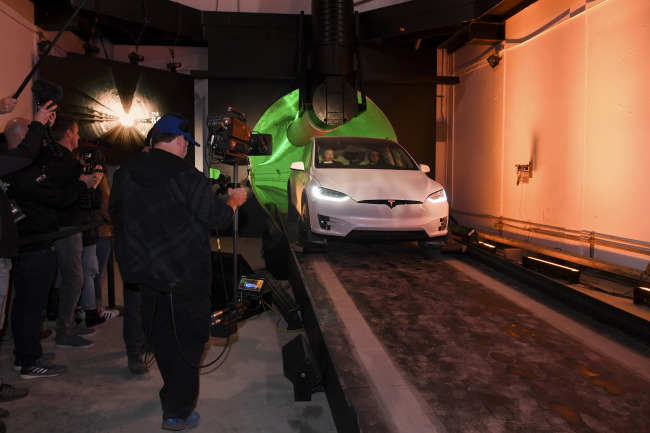 Elon Musk, co-founder and chief executive officer of Tesla Inc., arrives in a modified Tesla Model X electric vehicle during an unveiling event for the Boring Company Hawthorne test tunnel in Hawthorne, Calif., on Tuesday, Dec. 18, 2018. The tunnel, meant to be a "proof of concept," runs just over a mile under Musk's SpaceX headquarters in Hawthorne. [Photo: Pool via AP/Robyn Beck]