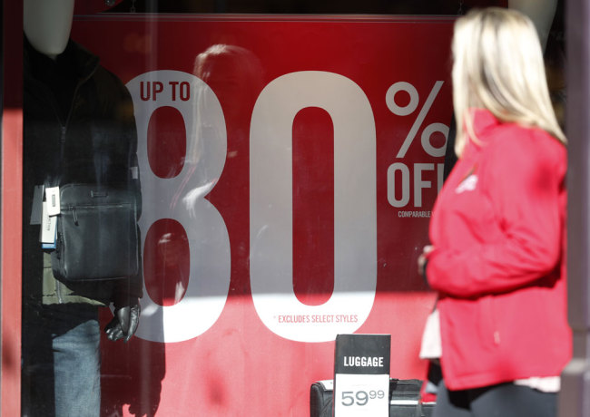 A placard advertises the discount available in a shop as last-minute shoppers finish up their Christmas gift lists at the Outlet Malls in Castle Rock Monday, Dec. 24, 2018, in Castle Rock, Colo. Retailers were offering ample discounts plus even more price cuts to those shoppers who ventured out with the holiday looming. [Photo:AP]