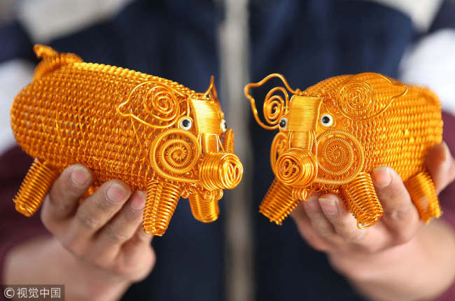 Two pig-shaped works(作品 zuòpǐn) weaved(编织 biānzhī) from aluminum by folk artist Cai Zhaowang are displayed(展示 zhǎnshì) in Linyi(临沂), Shandong province, Dec 26, 2018. [Photo/VCG]