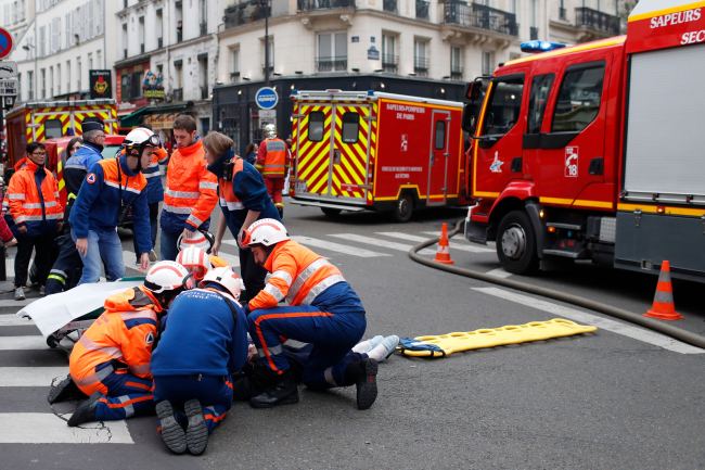 Firefighters tends to a wounded person near the site of a gas leak explosion in Paris, France, Saturday, Jan. 12, 2019. [Photo: AP /Thibault Camus]