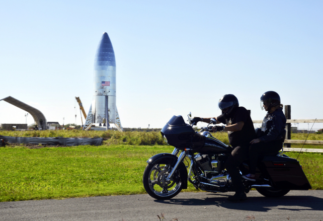 A motorcyclist rides near the SpaceX prototype Starship hopper at the Boca Chica Beach site in Texas, Jan. 12, 2019. [Photo: The Brownsville Herald via AP/Miguel Roberts]