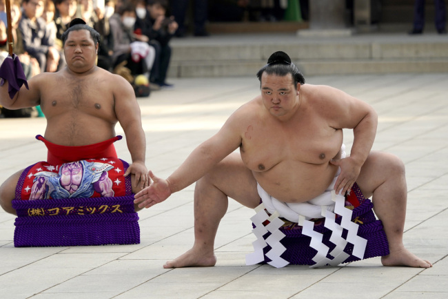 Sumo grand champion Kisenosato, right, of Japan performs his ring entry form with sward-holder Shohozan at the Meiji Shrine in Tokyo, Tuesday, Jan. 9, 2018. The Shinto ritual is part of the annual New Year's celebrations at the shrine. [Photo: AP]