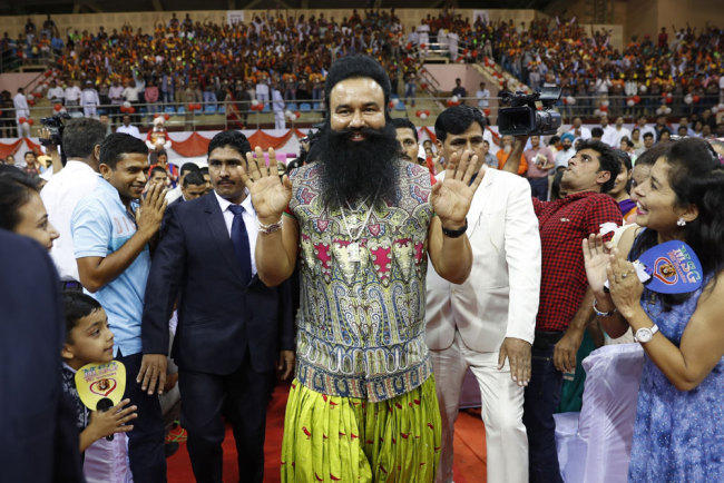 In this Oct. 5, 2016 file ., Indian spiritual guru who calls himself Dr. Saint Gurmeet Singh Ram Rahim Insan, center, greets followers as he arrives for a press conference ahead of the release of his new movie "MSG: The Warrior Lion Heart," in New Delhi, India. [Photo: IC]