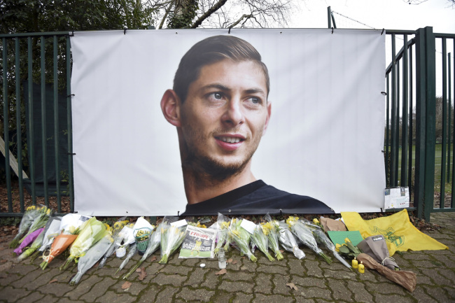 Flowers and tributes are placed near a giant picture of Argentine soccer player Emiliano Sala outside the FC Nantes training camp, in Nantes, western France, Thursday, Jan. 24, 2019, after a plane with Sala on board went missing over the English Channel on Monday night. Sobbing after the active search for her brother was halted, the sister of Argentine soccer player Emiliano Sala urged authorities Thursday not to give up trying to find the remains of his plane that disappeared from radar over the English Channel. [Photo: AP]