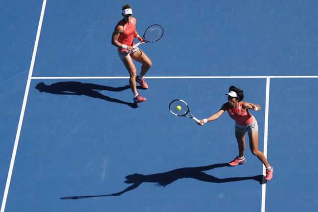 Australia's Samantha Stosur (L) watches as China's Zhang Shuai hits a return during the women's doubles final against Hungary's Timea Babos and France's Kristina Mladenovic on day 12 of the Australian Open tennis tournament in Melbourne on January 25, 2019. [Photo: AFP/David Gray]