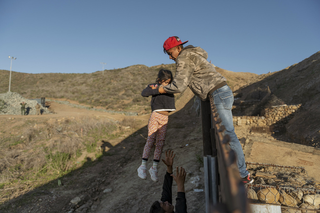 FILE - In this Jan. 3, 2019, file photo, a migrant from Honduras passes a child to her father after he jumped the border fence to get into the U.S. side to San Diego, Calif., from Tijuana, Mexico. The Trump administration says it would require extraordinary effort to reunite what may be thousands of migrant children who have been separated from their parents and, even if it could, the children would likely be emotionally harmed. [Photo: AP/Daniel Ochoa de Olza]