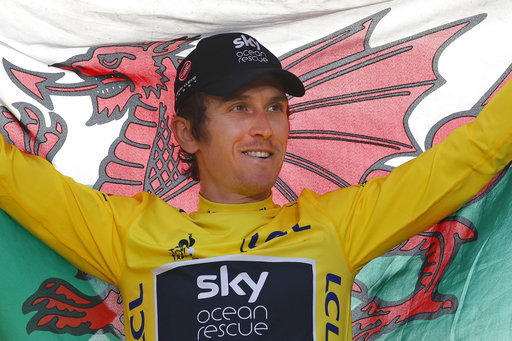 Geraint Thomas holds the Welsh flag on the podium after the twenty-first stage of the Tour de France cycling race on Champs-Elysees avenue in Paris, France on July 29, 2018.  [Photo: AP]