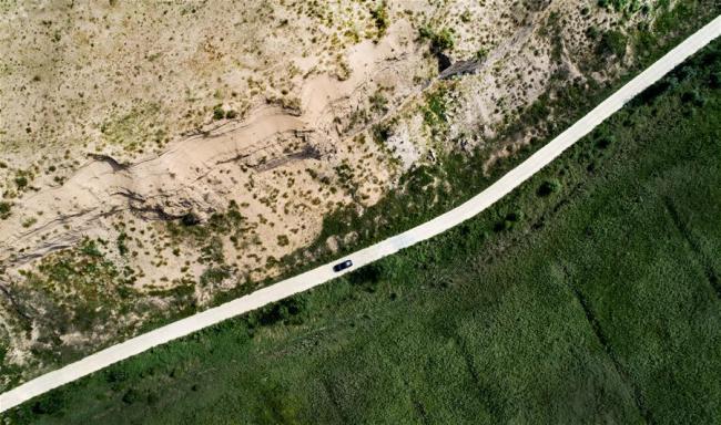 A car runs on a road that divides bare desert and desert under control in the Hengshan District of Yulin City, northwest China's Shaanxi Province, Aug. 4, 2018. [Photo: Xinhua]