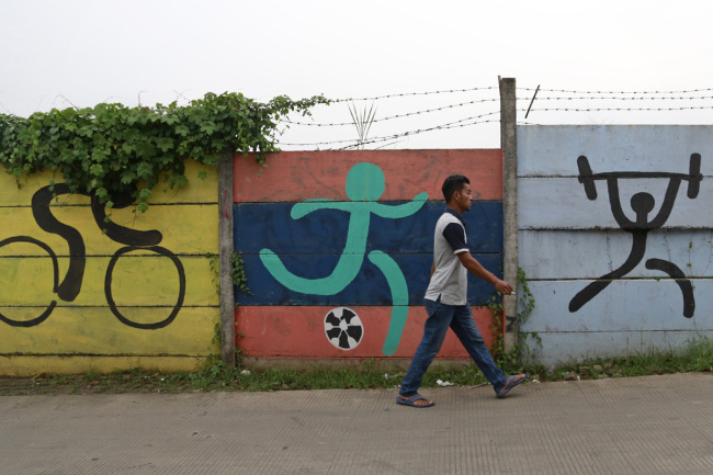 A man walks past sports murals originally painted on a wall as promotional tools for the 2018 Asian Games in Jakarta, Indonesia, Tuesday, Feb. 19, 2019. [Photo: AP]