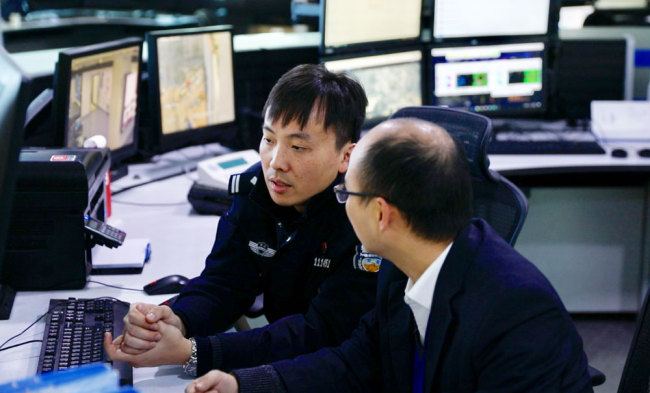 Traffic policeman Yu Limin (L) discusses the operation of the Hangzhou "City Brain" with an engineer at a control center in the city. [Photo: China Plus]