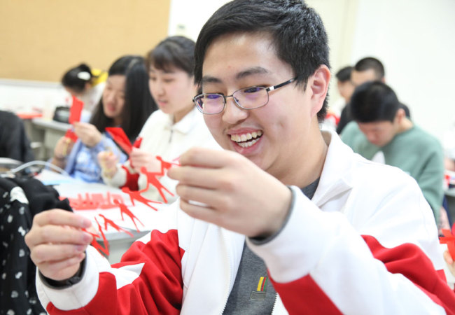 A student happy with his creation in an elective class on paper-cutting at the High School Affiliated to Renmin University of China in Beijing on Thursday, March 7, 2019. [Photo: China Plus]