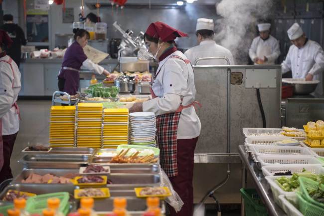 Staff at a restaurant at Zhejiang Gongshang University prepare(准备 zhǔnbèi) dishes for students on Wednesday, March 13, 2019. [Photo: IC]