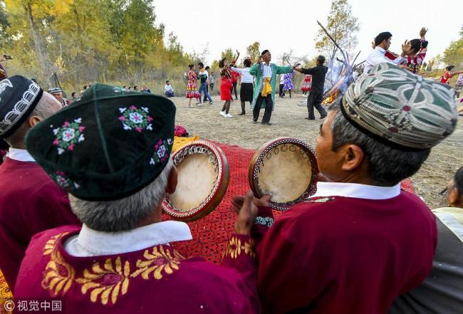 Local people in Aksu Prefecture in Northwest China's Xinjiang Uyghur Autonomous Region gather after work to perform Mexrep, a kind of traditional Uygur folk custom that consists of songs, dances and games, on October 8, 2018. [Photo: VCG]