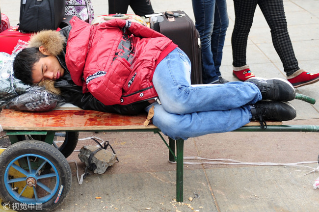  The undated picture shows a young man sleeping on his cart which he also uses as a booth to sell things. [File Photo:VCG]