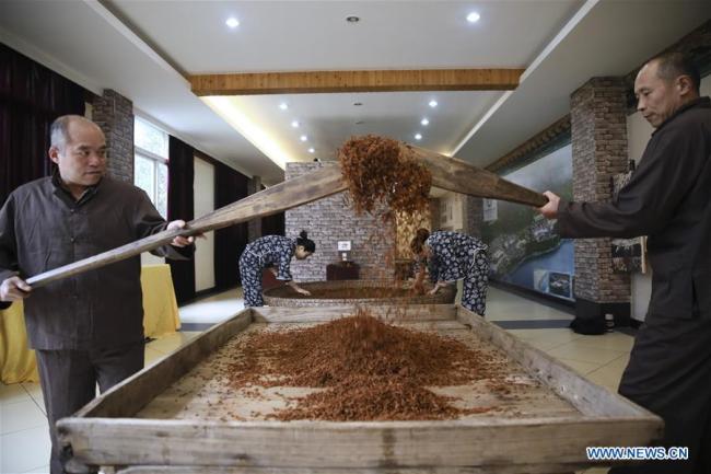 Li Wenlin (1st R), an inheritor of the national level intangible cultural heritage Fuling pickle, and his assistant process ingredients(调料 tiáoliào) at a workshop in Chongqing, southwest China, Feb. 22, 2019.[Photo: Xinhua/Lan Hongguang]