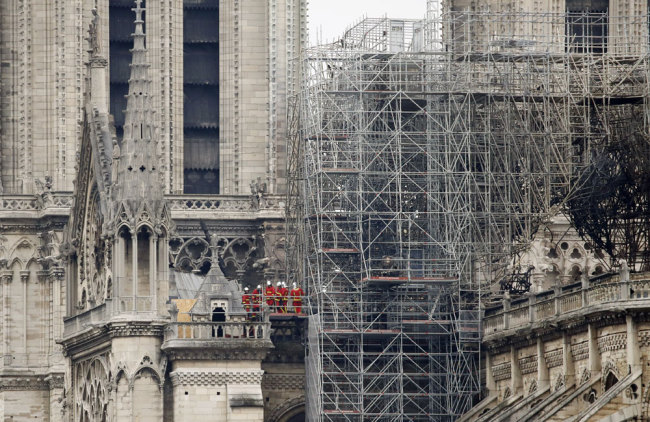 Firemen inspect the Notre Dame cathedral after the fire in Paris, Tuesday, April 16, 2019. [Photo: AP/Christophe Ena]