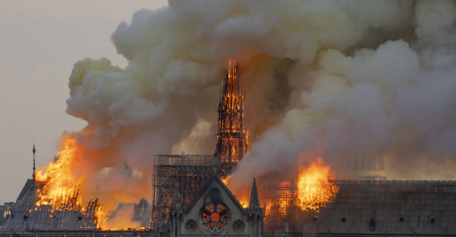 Smoke billows as flames burn through the roof of the Notre-Dame de Paris Cathedral on April 15, 2019. [Photo:AFP/Fabien Barrau]
