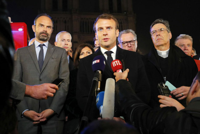 French President Emmanuel Macron (C) is accompanied by Mayor of Paris Anne Hidalgo (3L), French Prime Minister Edouard Philippe (L), French Culture Minister Franck Riester (2L) and Archbishop of Paris Michel Aupetit as he speaks at Notre-Dame Cathedral in Paris on April 15, 2019, after a fire engulfed the building. [Photo: AFP/Philippe Wojazer]