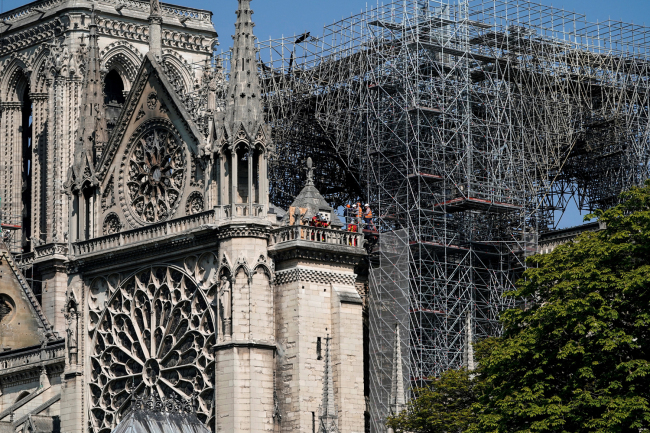 Firefighters and technicians work on a balcony of Notre-Dame de Paris Cathedral in Paris on April 19, 2019, four days after a fire devastated the cathedral. [Photo: AFP]