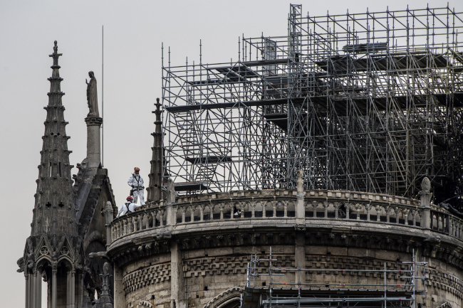 Workers stand on the roof of the Notre-Dame de Paris cathedral in Paris on April 23, 2019, one week after a fire devastated the cathedral. [Photo: AFP]