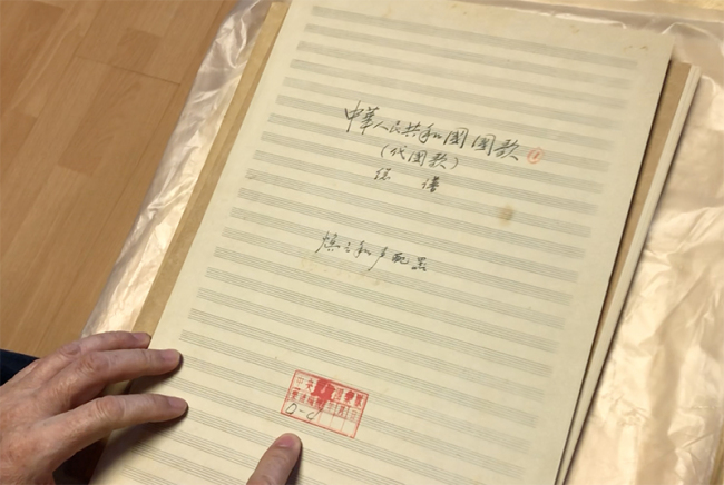 Li Dakang showed China Plus reporter the duplicate of his father’s original orchestral score of the National Anthem, 'the March of the Volunteers’. [Photo by China Plus/Yang Yong]